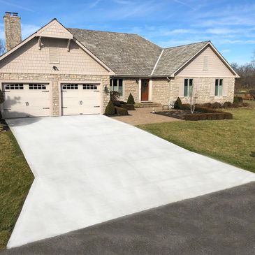 A suburban house with a freshly poured white concrete driveway.