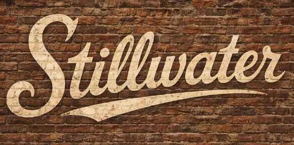 The word 'Stillwater' painted on a brick wall.