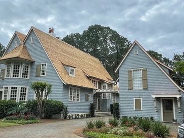 A charming blue house with a unique roof that is another great example of why we are the best roofers in Destin.