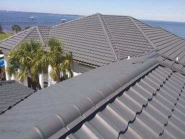 Gray tiled roof with ocean view and palm trees.