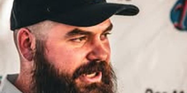 Bearded man wearing a black cap looking to the side.
