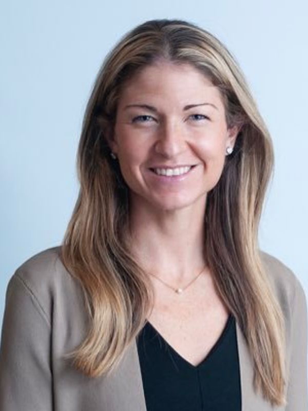 Smiling woman with long blonde hair in professional attire.