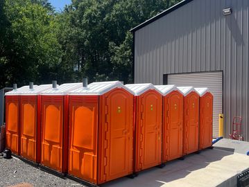 Row of orange portable toilets near a building.