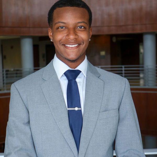 Young man in a gray suit smiling.