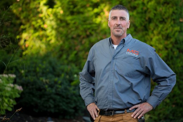 Confident man in work attire posing outdoors with hands on hips.