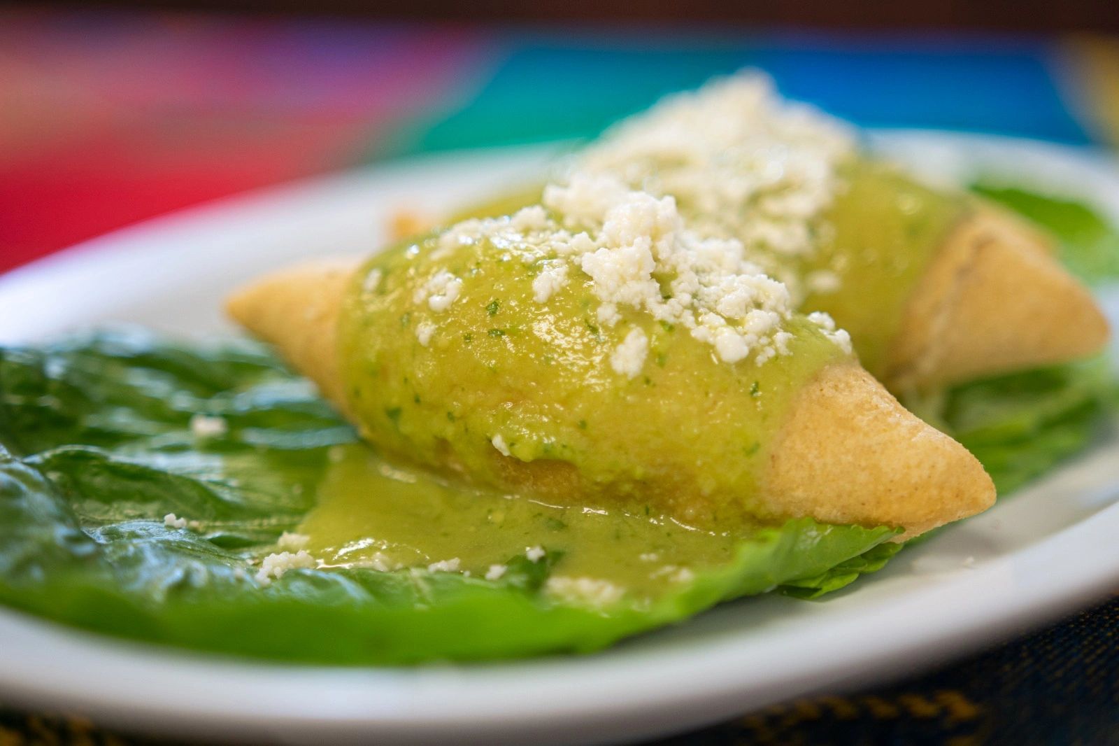 Deep fried corn tortillas with cheese sprinkled over a green lettuce leaf