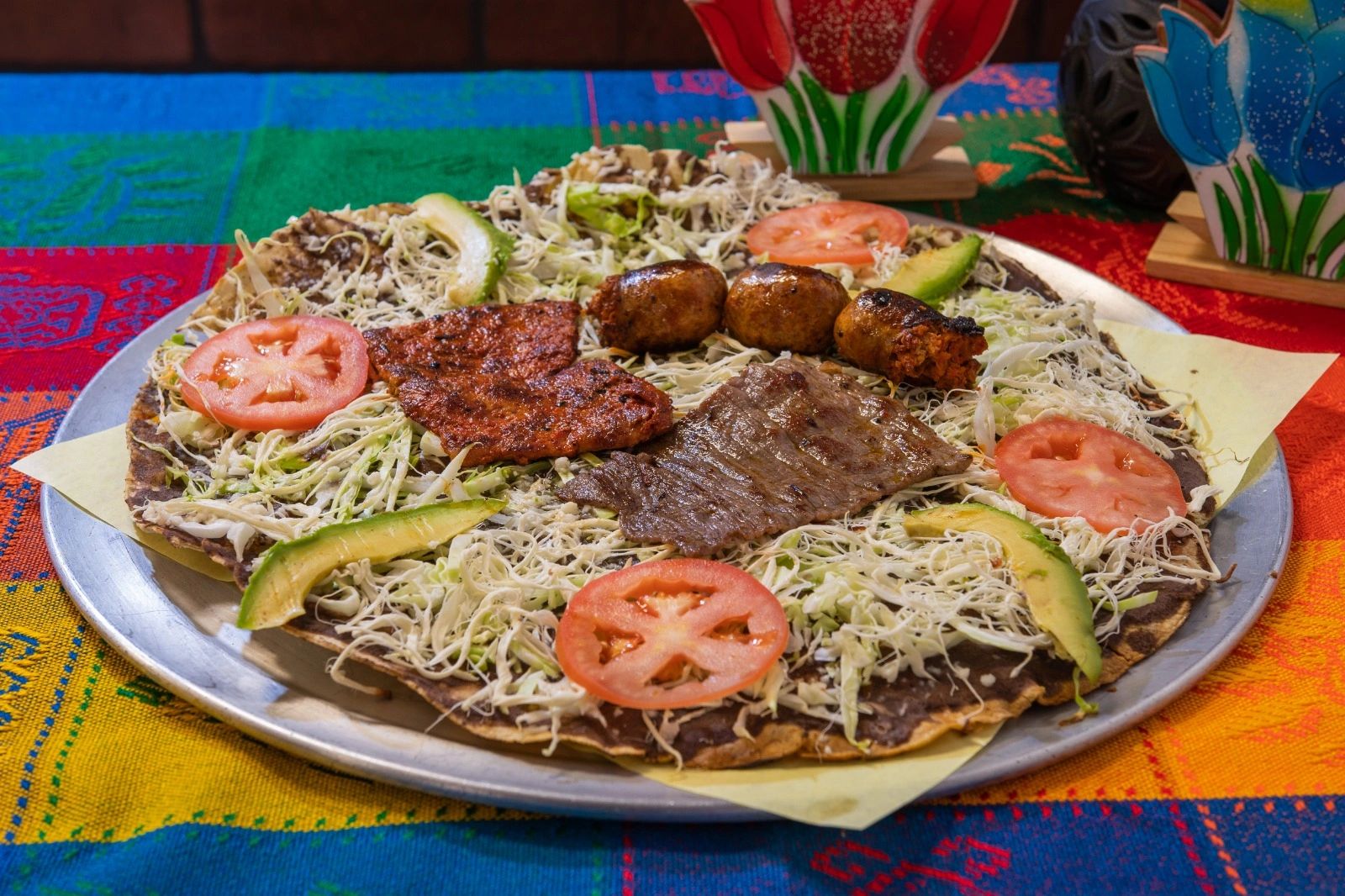 Traditional Mexican dish called Tlayuda on a table with a colorful table cloth