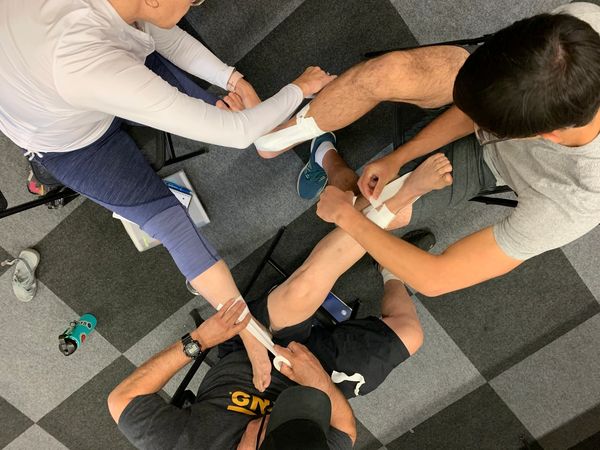 Three people taping legs from a top view.