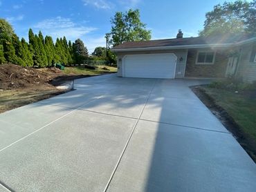 Broom finish concrete driveway with large parking area to side of garage.