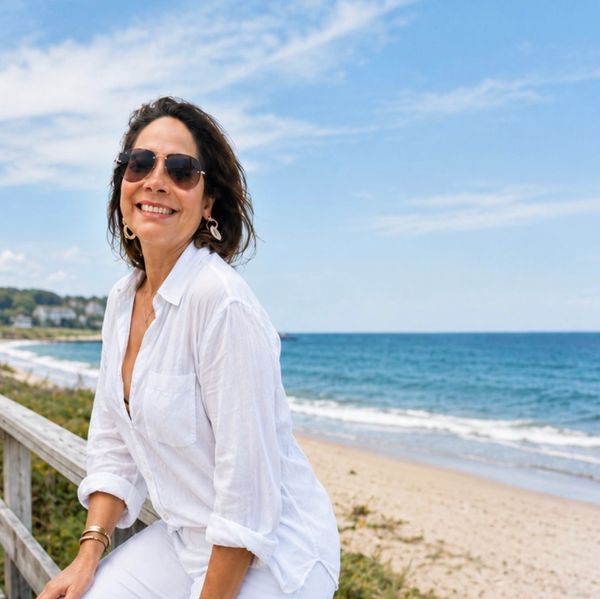 Mujer sonriente con gafas de sol en la playa.