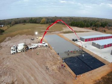 Concrete pouring at a construction site with a large red boom pump and workers.