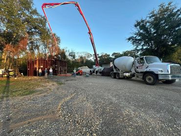 Workers pour concrete into a large formwork using a concrete pump truck.