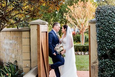 Bride and groom share a loving moment at garden entrance on their wedding day.