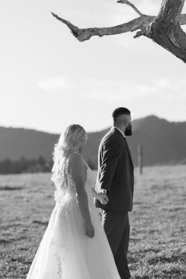 Bride and groom holding hands in a serene outdoor setting.
