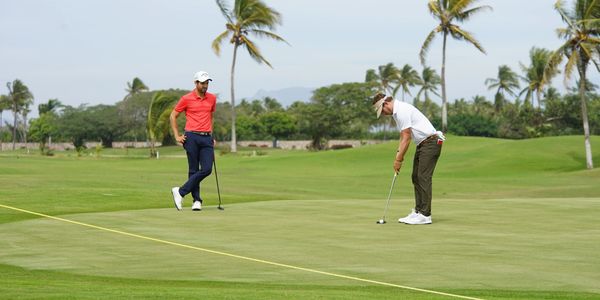 Dos hombres jugando golf en un campo verde.