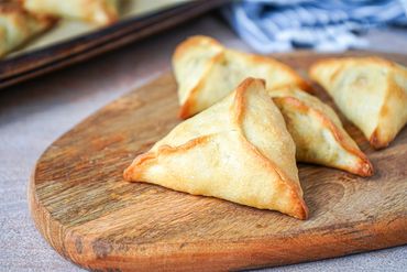 Golden-brown triangular pastries on a wooden board.