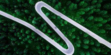 An overhead shot of a twisting road with a single car