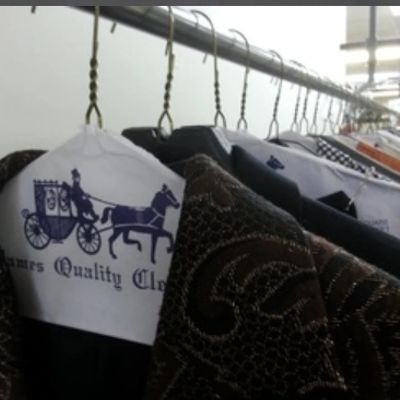 Clothes hanging on hangers with dry cleaning covers in a row.
