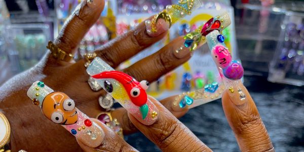 Colorful, 3D cartoon character nail art on hands with rings.