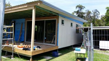 Small house under construction with tools and scaffolding outside.