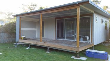 A modern small house with a wooden deck under construction.