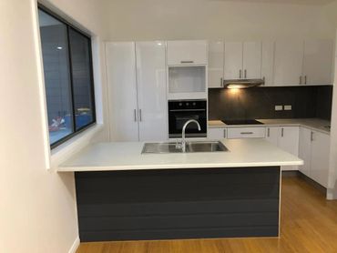 Modern kitchen with white cabinets, black backsplash, and island sink.