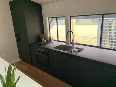 Modern kitchen with matte black cabinets and wooden floor.
