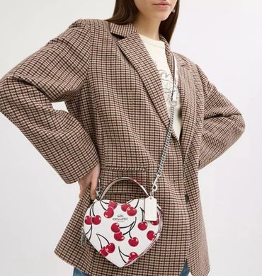 Crossbody en forma de corazon, color blanco con estampado de cerezas, marca Coach
