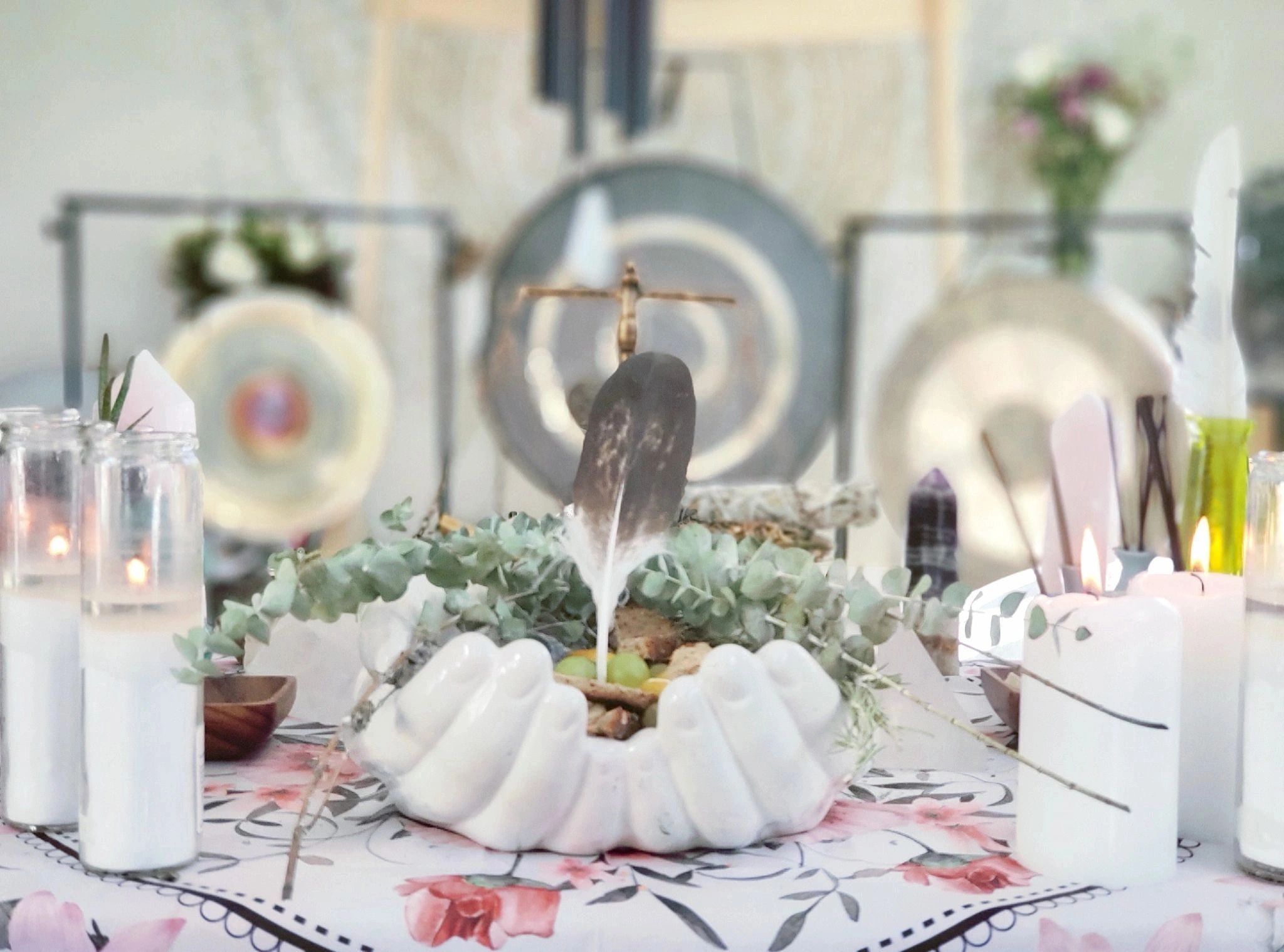 A spiritual altar with candles, feathers, and gongs in the background.