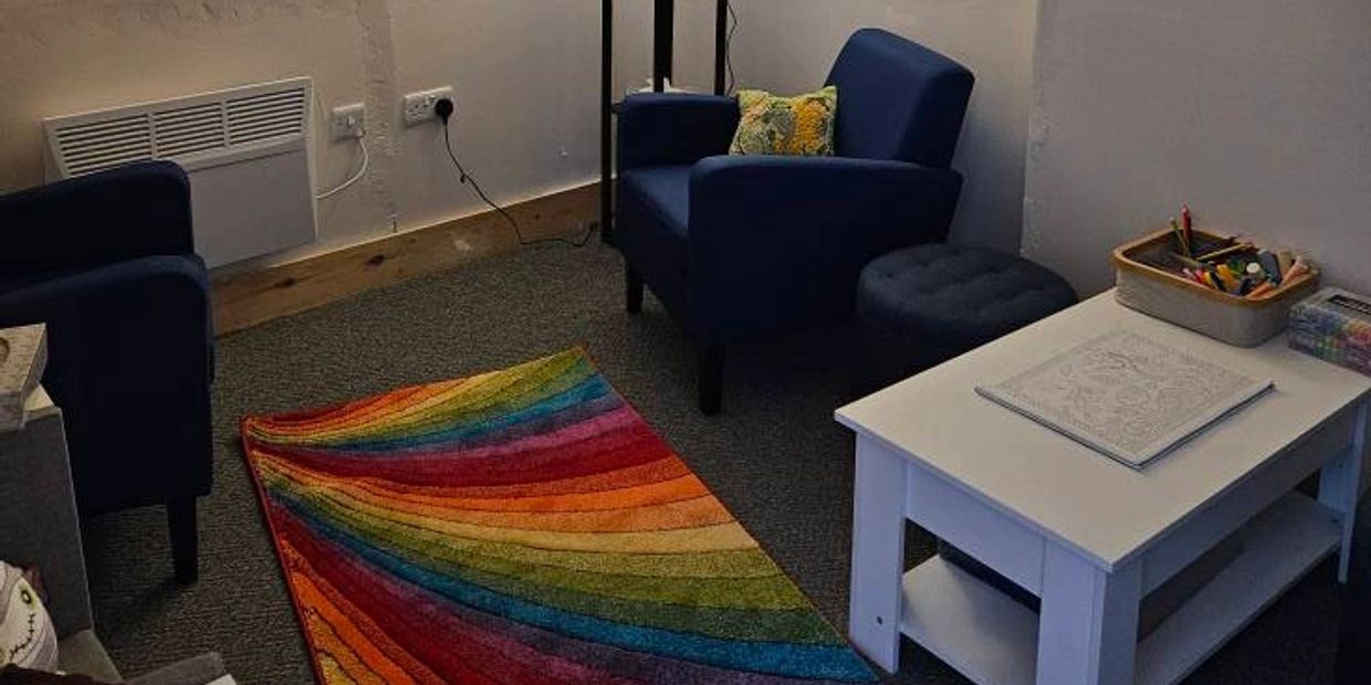 Cozy room with blue chairs and a colorful rainbow rug on the floor.