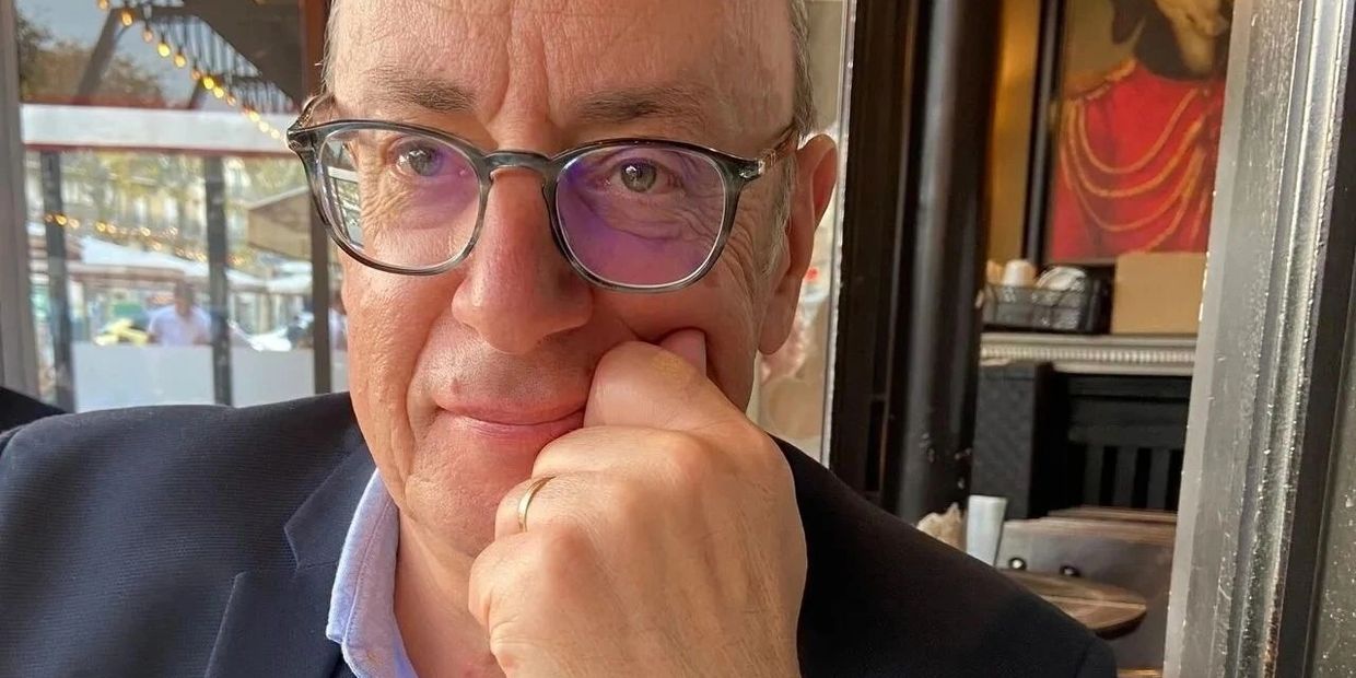 Homme portant des lunettes avec une bague en or, pensif.