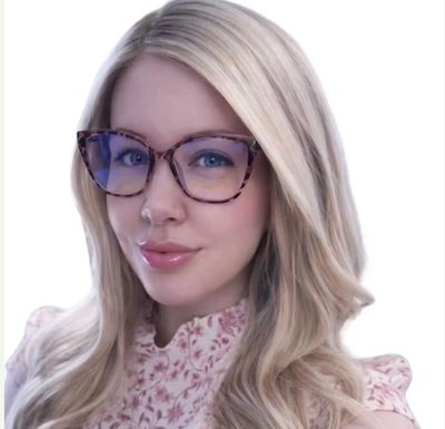 Blonde woman with glasses and floral top smiling.