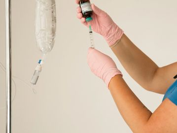 Medical professional preparing an IV drip with gloves.