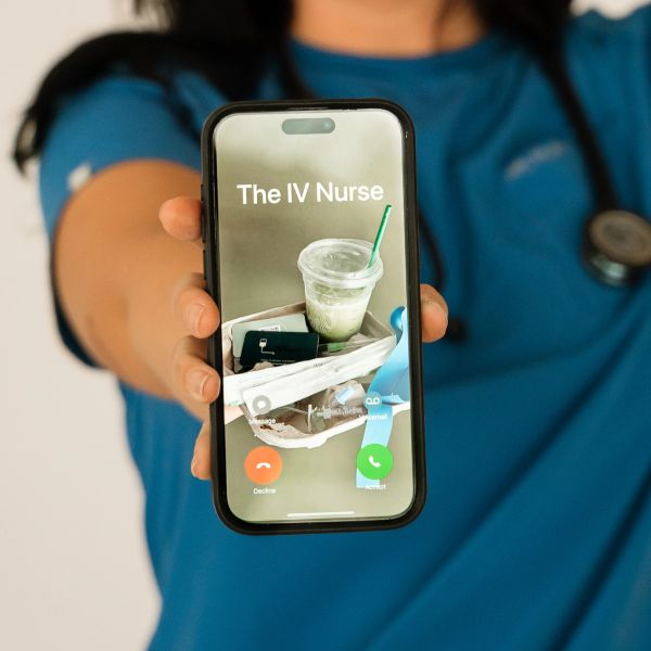 Person in scrubs holding phone with "The IV Nurse" on screen.