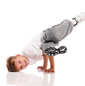 Young boy performing a breakdance move with a smile.