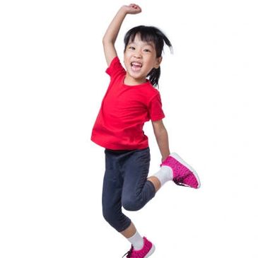 Joyful young girl jumping with excitement wearing a red shirt and pink shoes.