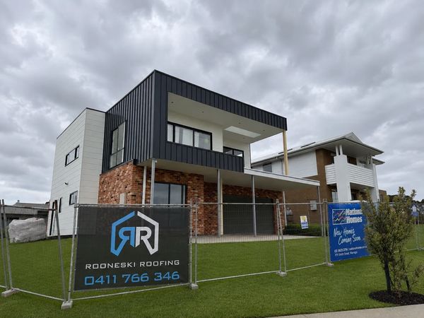 Modern two-story house under cloudy sky with construction signs.