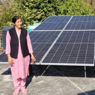 Woman standing beside solar panels in a sunny outdoor setting.
