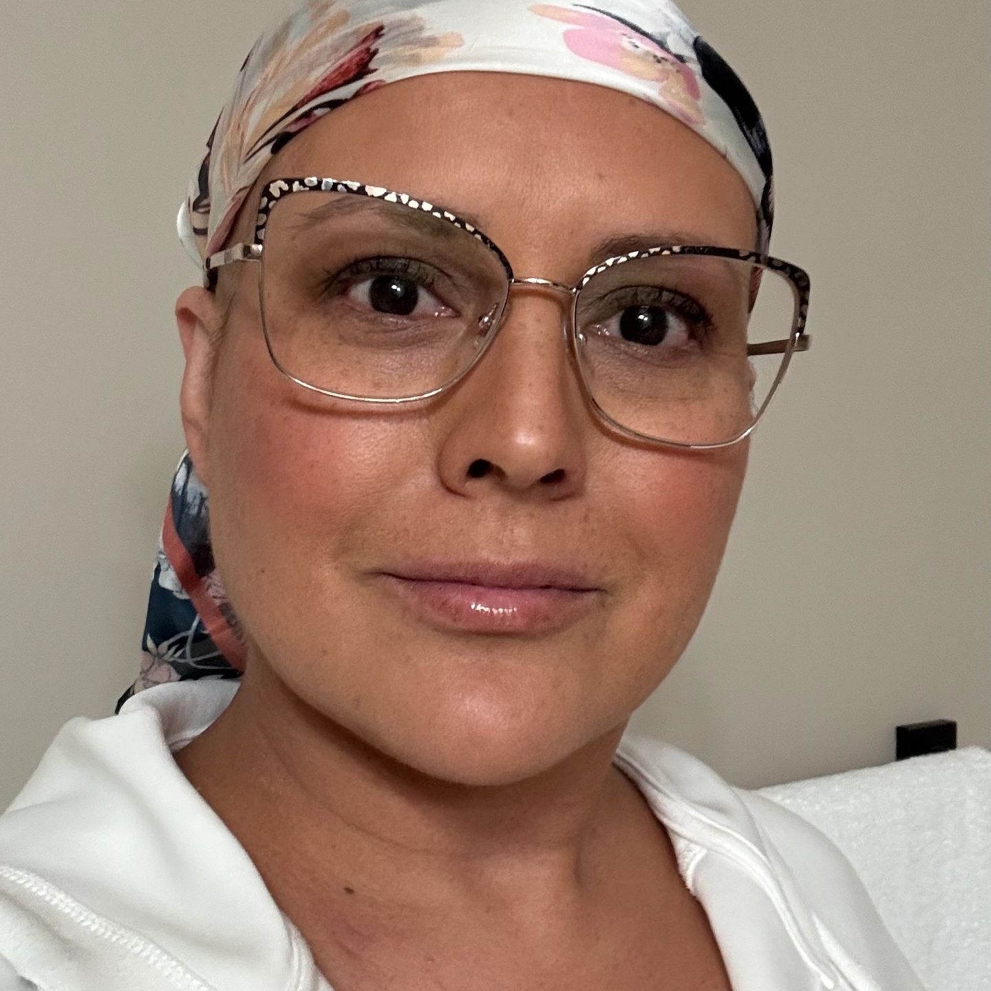 Close-up of a woman wearing glasses and a floral headscarf.
