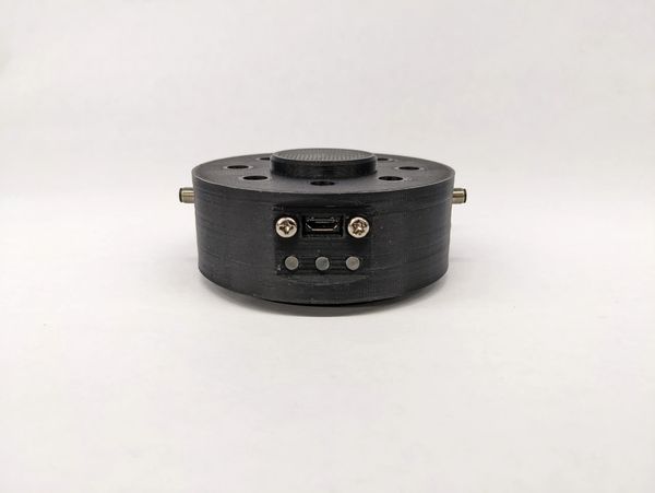 A black circular electronic device with buttons and a USB port.