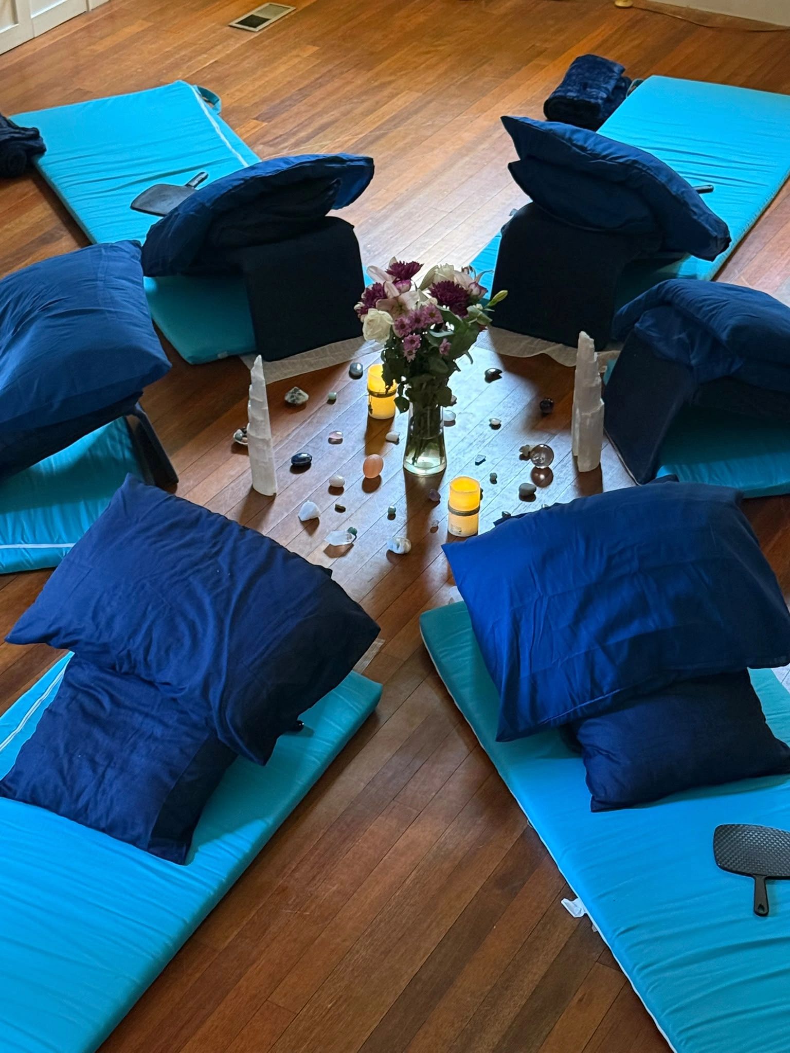Meditation setup with cushions, candles, and crystals arranged around flowers.