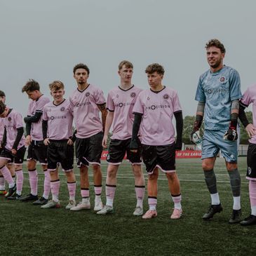 Soccer team lined up in pink and black uniforms.