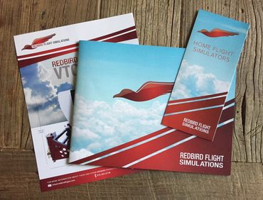 Redbird Flight Simulations brochures on a wooden surface.
