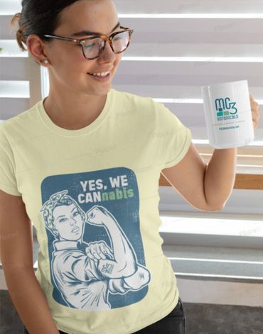 Smiling woman wearing glasses, holding a mug, and a cannabis-themed graphic t-shirt.