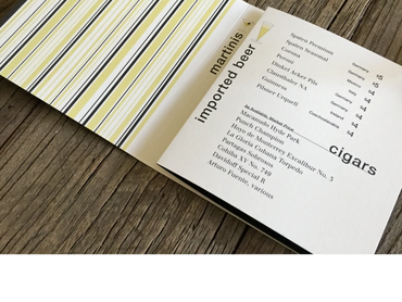 A stylish menu displaying imported beers and cigars on a wooden table.