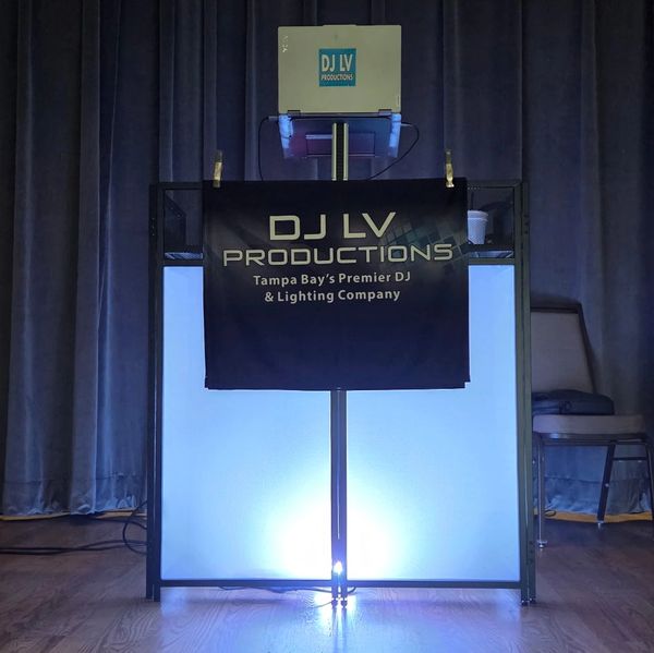 DJ LV Productions setup on stage with glowing blue light and black backdrop.