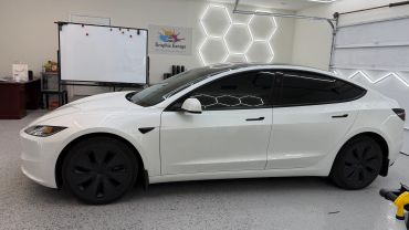 White Tesla Model 3 inside a garage with hexagonal LED lights.