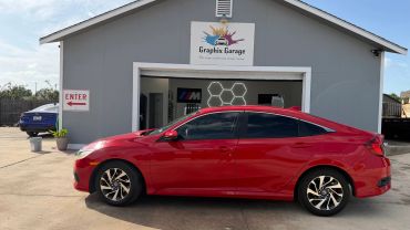 Red car parked outside a garage named Graphix Garage.