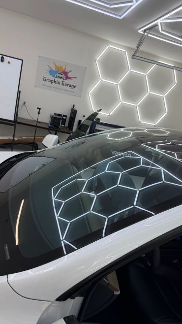 Modern car with hexagonal light reflection in a garage.