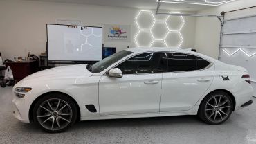 White car inside a garage with hexagonal lights on the wall.